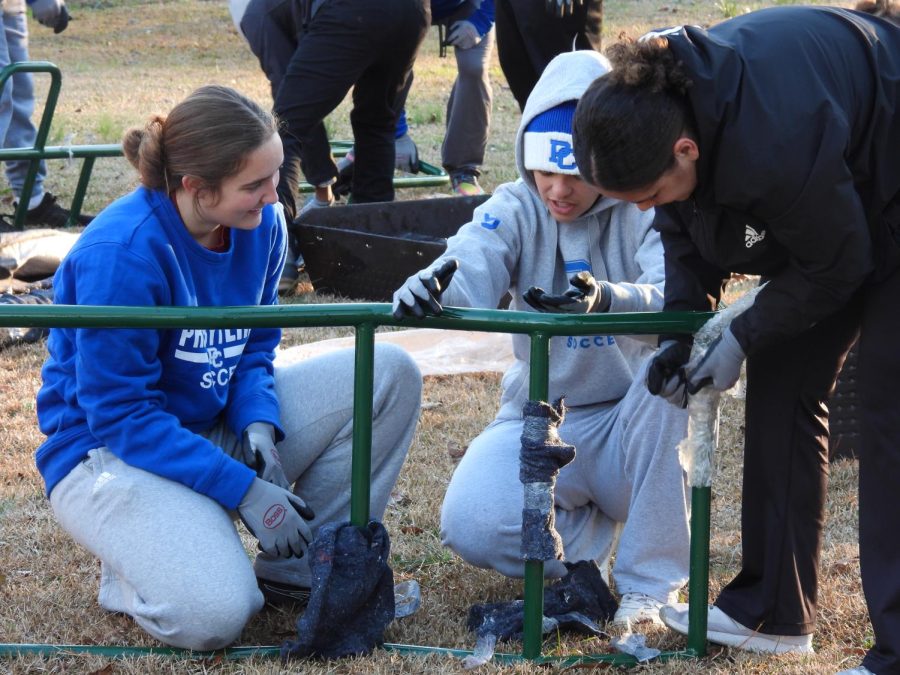 Blue Hose womens soccer player Kelly Hall (left) works with volunteers on unwrapping the playgrounds ladder.