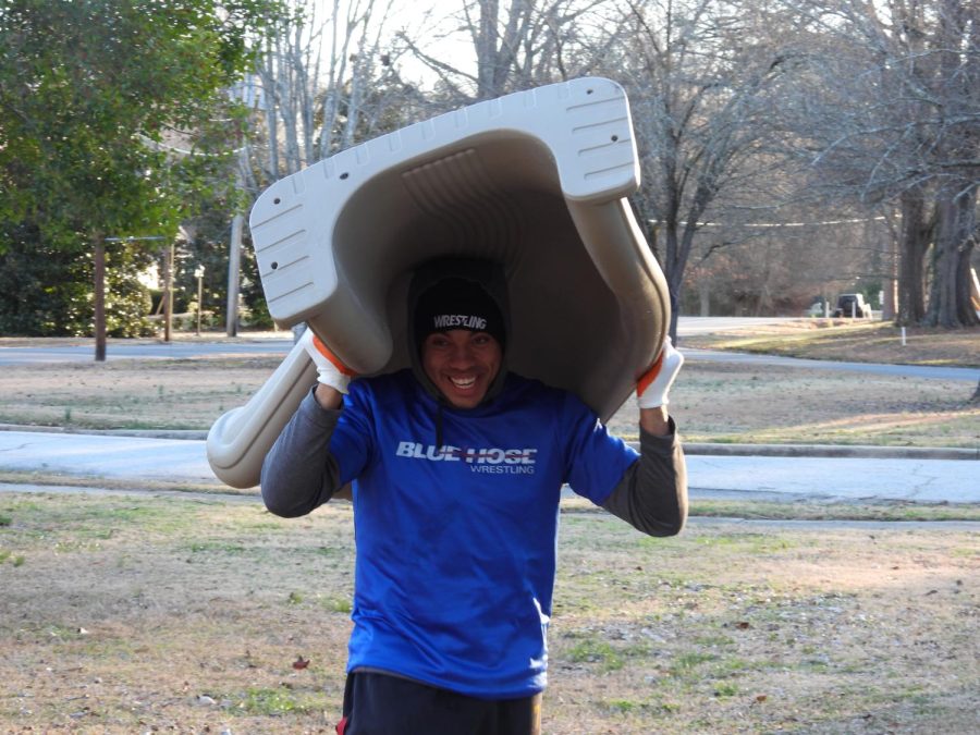 A member of the Blue Hose mens wrestling team carries a part of the playgrounds slide.